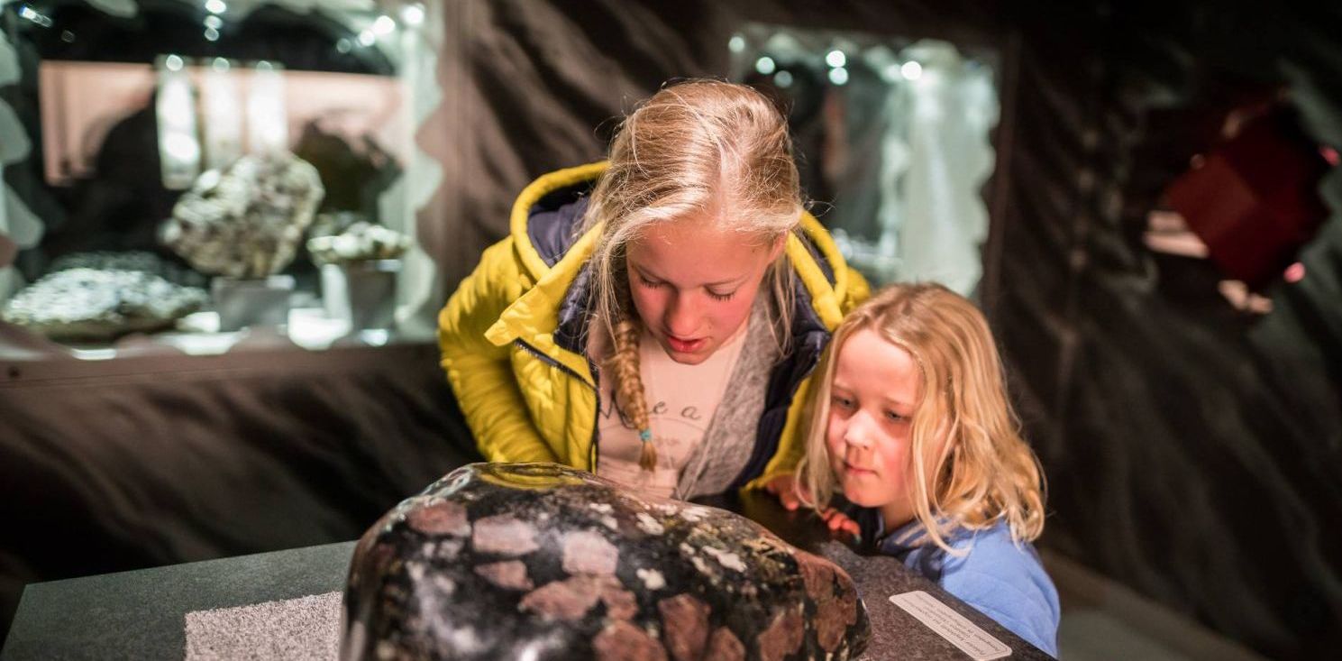 Zwei Kinder schauen sich im Granatmuseum in Radenthein einen Granatstein an.