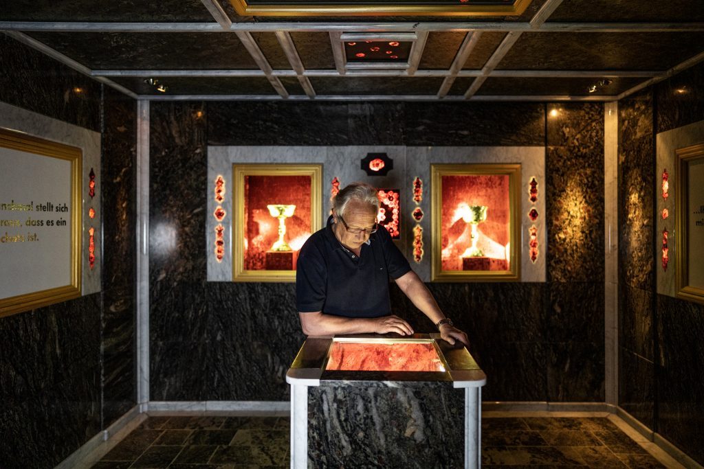 Ein Mann steht im Granatzimmer in der Erlebniswelt Granatium und bewundert einen Granatstein. Ein Mann steht im Granatzimmer in der Erlebniswelt Granatium und bewundert einen Granatstein.