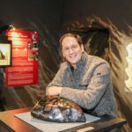 Manfred König, der Geschäftsführer der Erlebniswelt Granatium in Radenthein, steht im Granatmuseum und lehnt sich an einem Granatstein an.