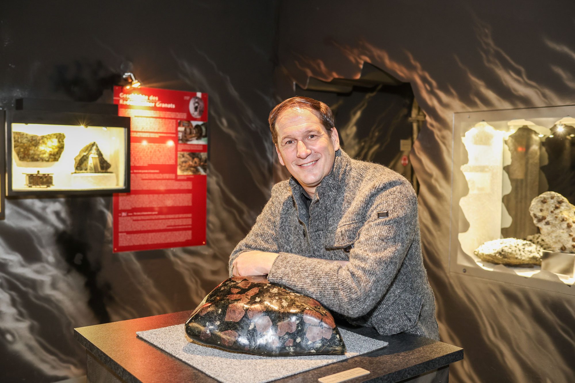 Manfred König, der Geschäftsführer der Erlebniswelt Granatium in Radenthein, steht im Granatmuseum und lehnt sich an einem Granatstein an.