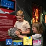 Zwei Kinder stehen im Granatmuseum und greifen einen Stein an.