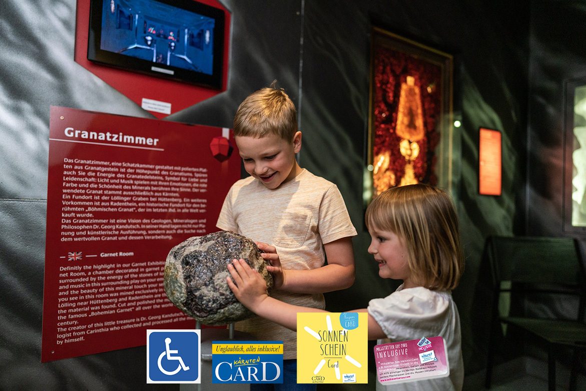 Two children are standing in the grenade museum, picking up a stone.