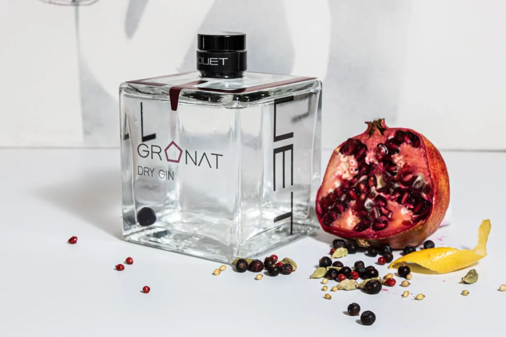 Eine Flasche mit Granatgin, daneben ein Granatapfel
