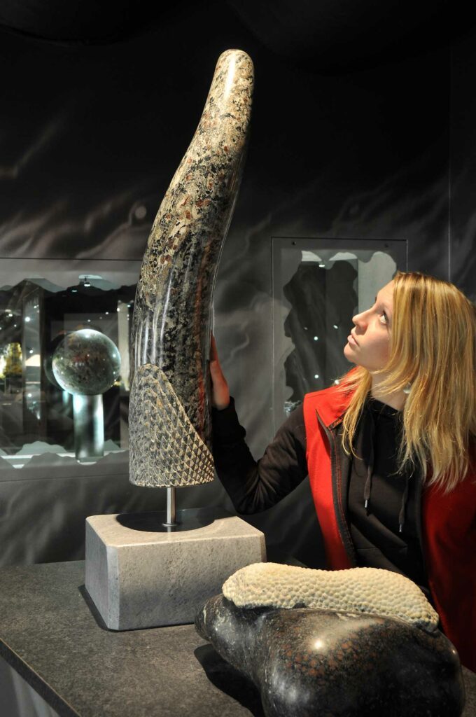 Eine Frau sieht sich eine Granatsteinskulptur an. Eine Frau sieht sich eine Granatsteinskulptur an.