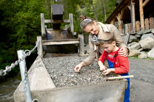 Ein Kind und eine Frau schürfen im Schürfgelände in der Erlebniswelt Granatium nach Granatsteinen.