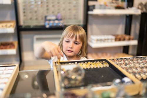 Ein kleines Mädchen sieht sich im Granatium Shop Schmuck an.