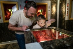 Ein Mann und ein Bub bewundern im Granatzimmer einen Granatstein.