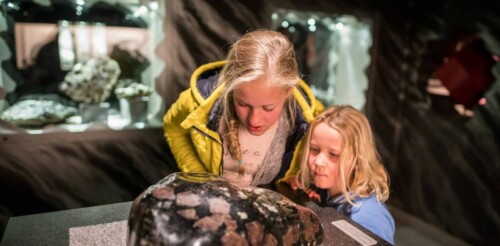 Zwei Kinder schauen sich im Granatmuseum in Radenthein einen Granatstein an.
