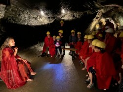 Die Bergfee Granatia sitzt mit Kindern im Karfunkelstollen in Radenthein und erzählt eine Geschichte.
