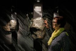 Eine Frau steht im Granatmuseum und fasst einen großen Granatstein an.