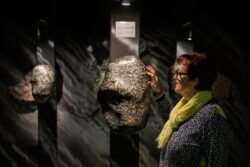 Eine Frau steht im Granatmuseum und fasst einen großen Granatstein an.