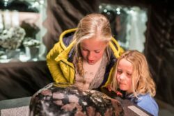 Zwei Kinder schauen sich im Granatmuseum in Radenthein einen Granatstein an.