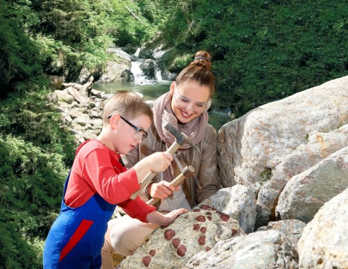 Ein Kind und eine Frau schürfen einen Granatstein mit einem Hammer.