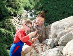 Ein Kind und eine Frau schürfen einen Granatstein mit einem Hammer.