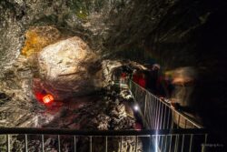 Eine Gruppe von Erwachsenen steht im Stollen im Granatium und sieht sich einen roten, beleuchteten Granatstein an.
