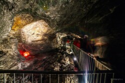 Eine Gruppe von Erwachsenen steht im Stollen im Granatium und sieht sich einen roten, beleuchteten Granatstein an.